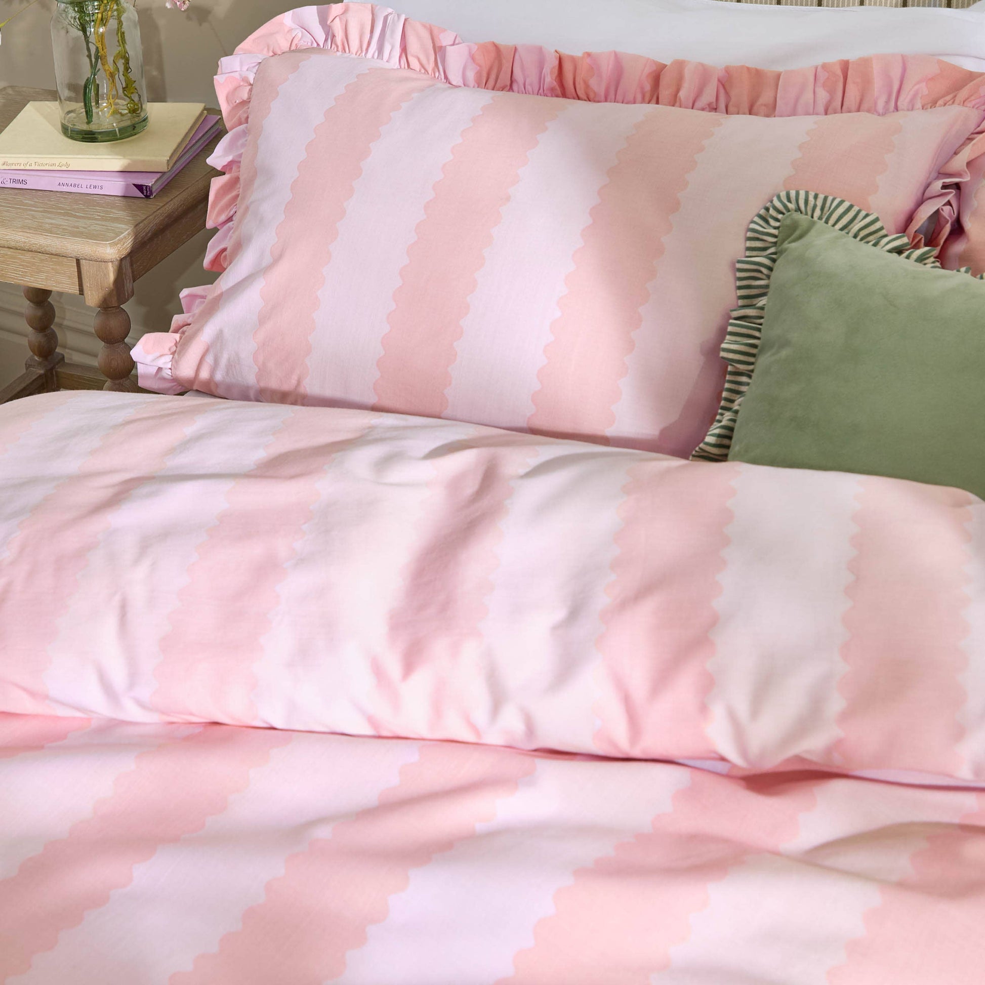 Pink and white striped bedding with a side table in the background