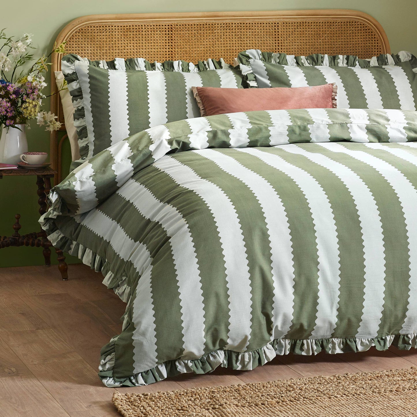 Green and white striped bedding on a bed with a wooden headboard and side table.