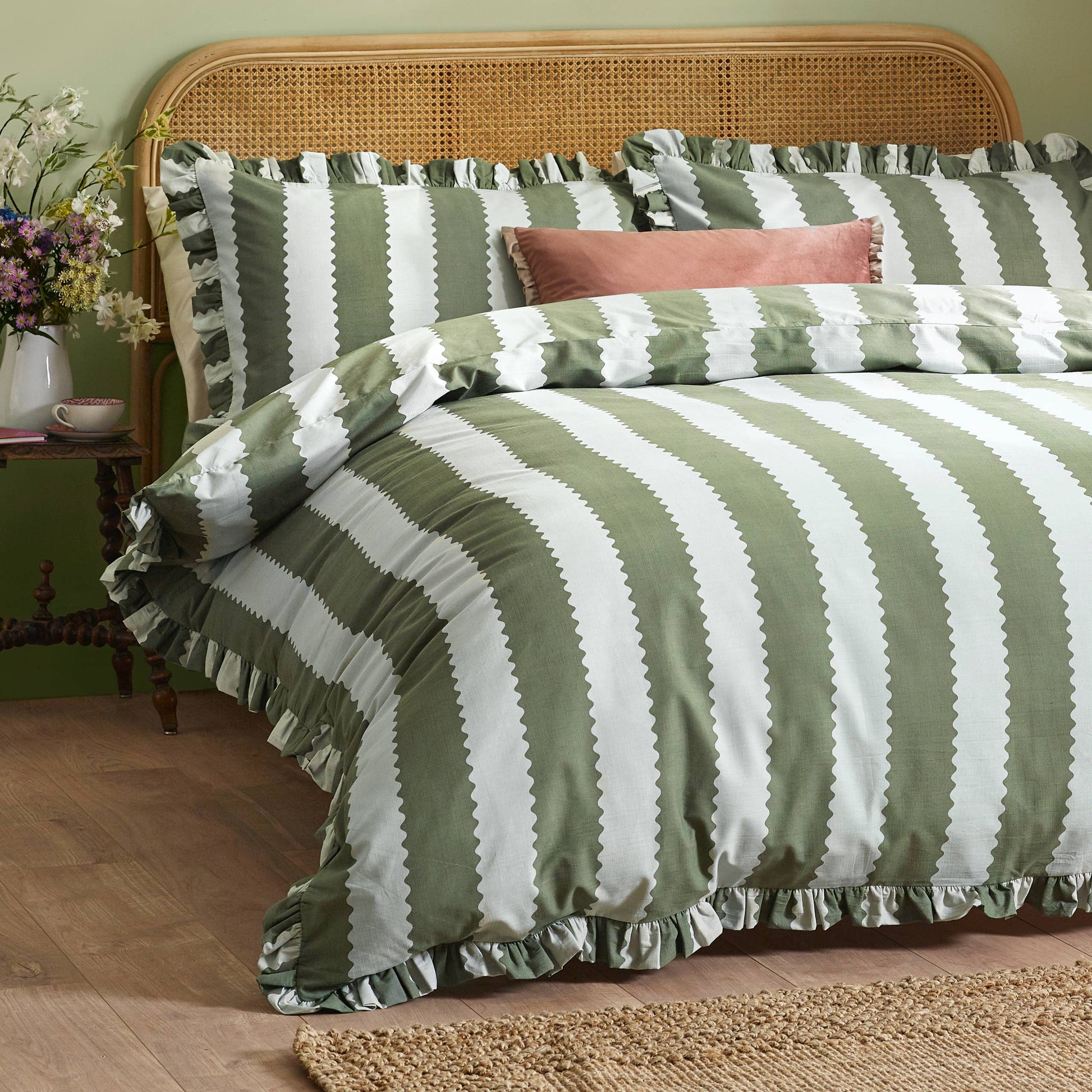 Green and white striped bedding on a bed with a wooden headboard and side table.