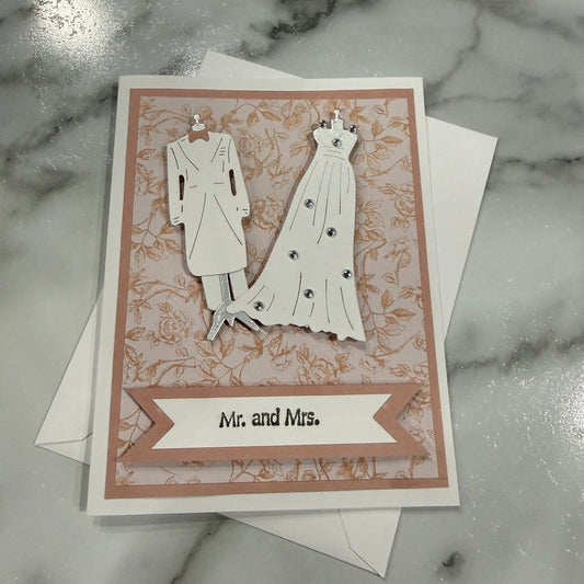 Greeting card with wedding dress and 'Mr. and Mrs.' text on a marble surface