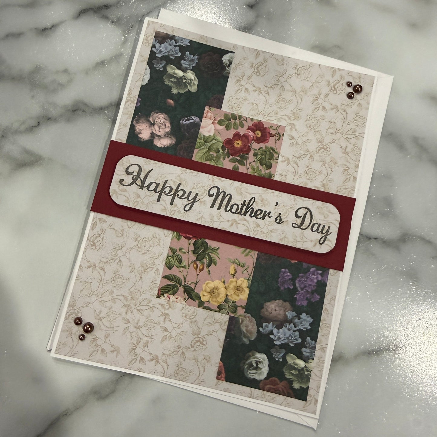 Greeting card with floral designs and 'Happy Mother's Day' text on a marble surface