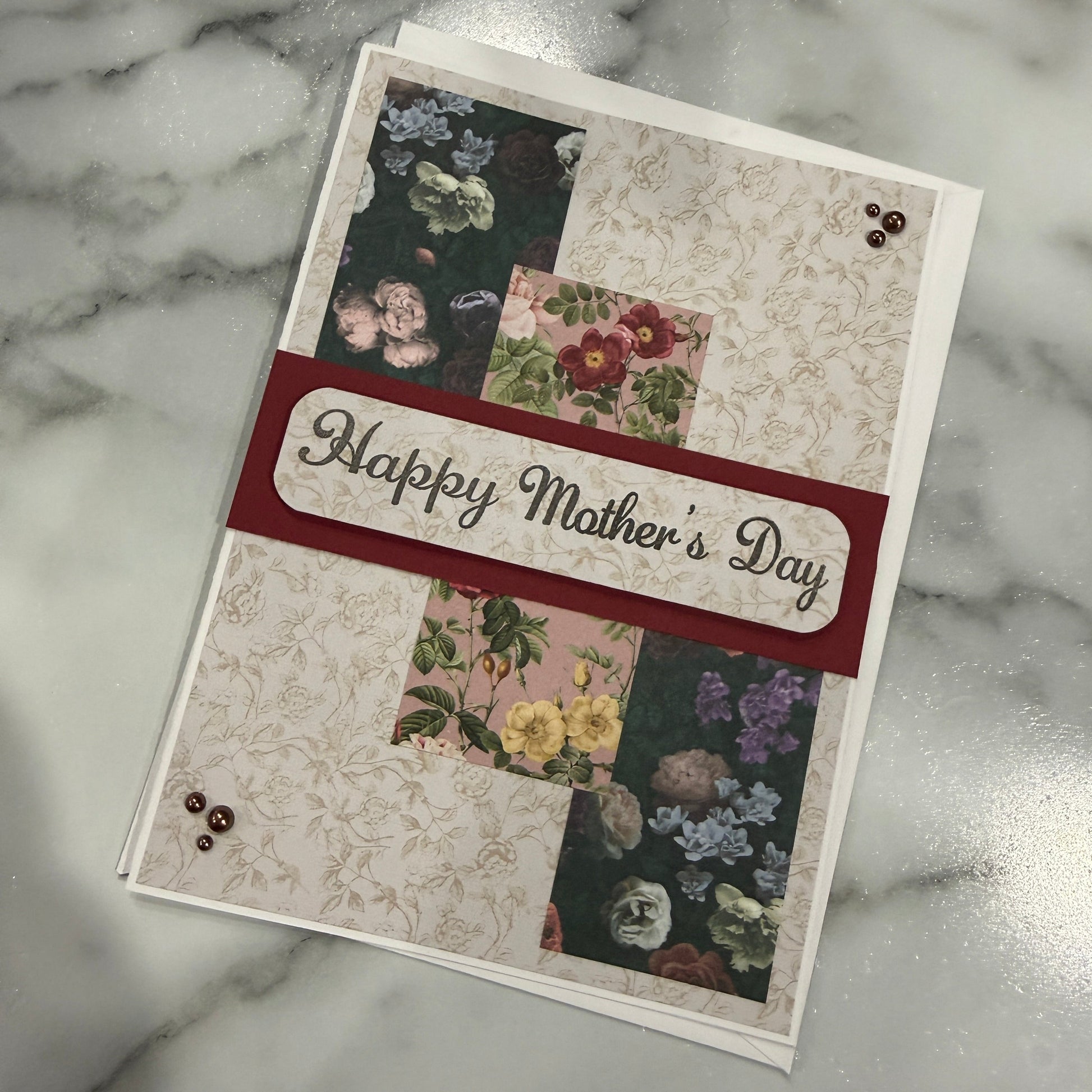 Greeting card with floral designs and 'Happy Mother's Day' text on a marble surface