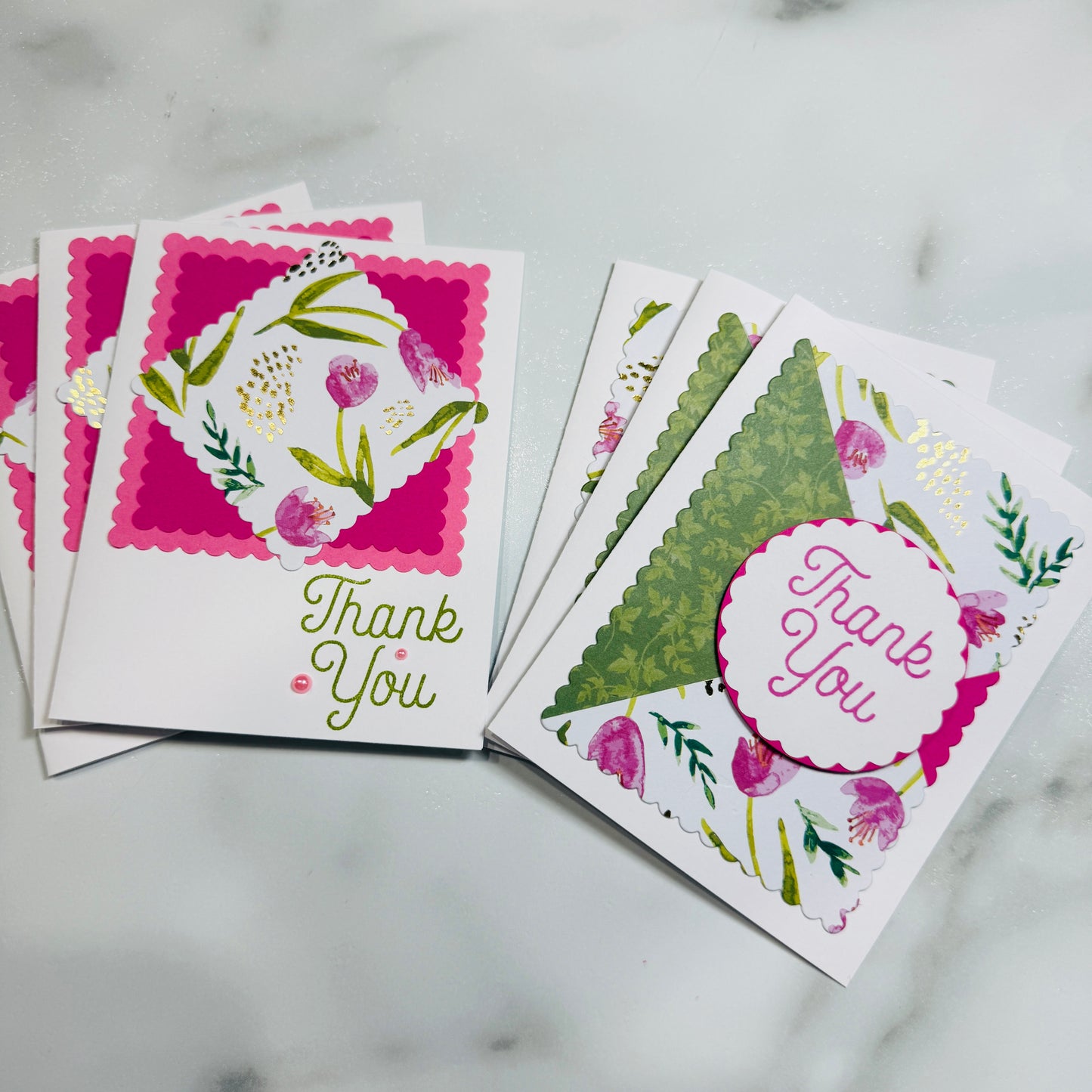 Two handmade thank you cards with floral designs and scalloped edges, displayed on a light marble surface.