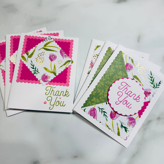 Two handmade thank you cards with floral designs and scalloped edges, displayed on a light marble surface.