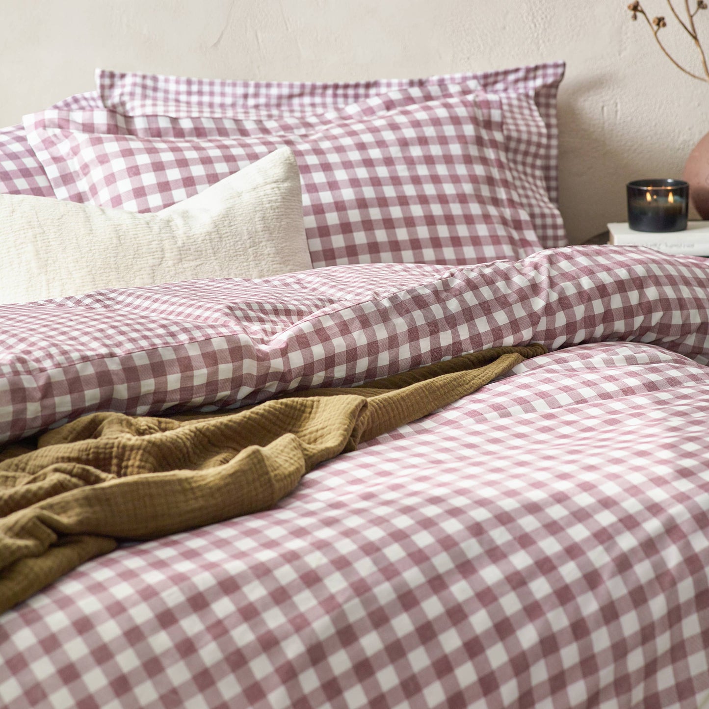 Bed with berry and white checkered bedding and a yellow blanket.