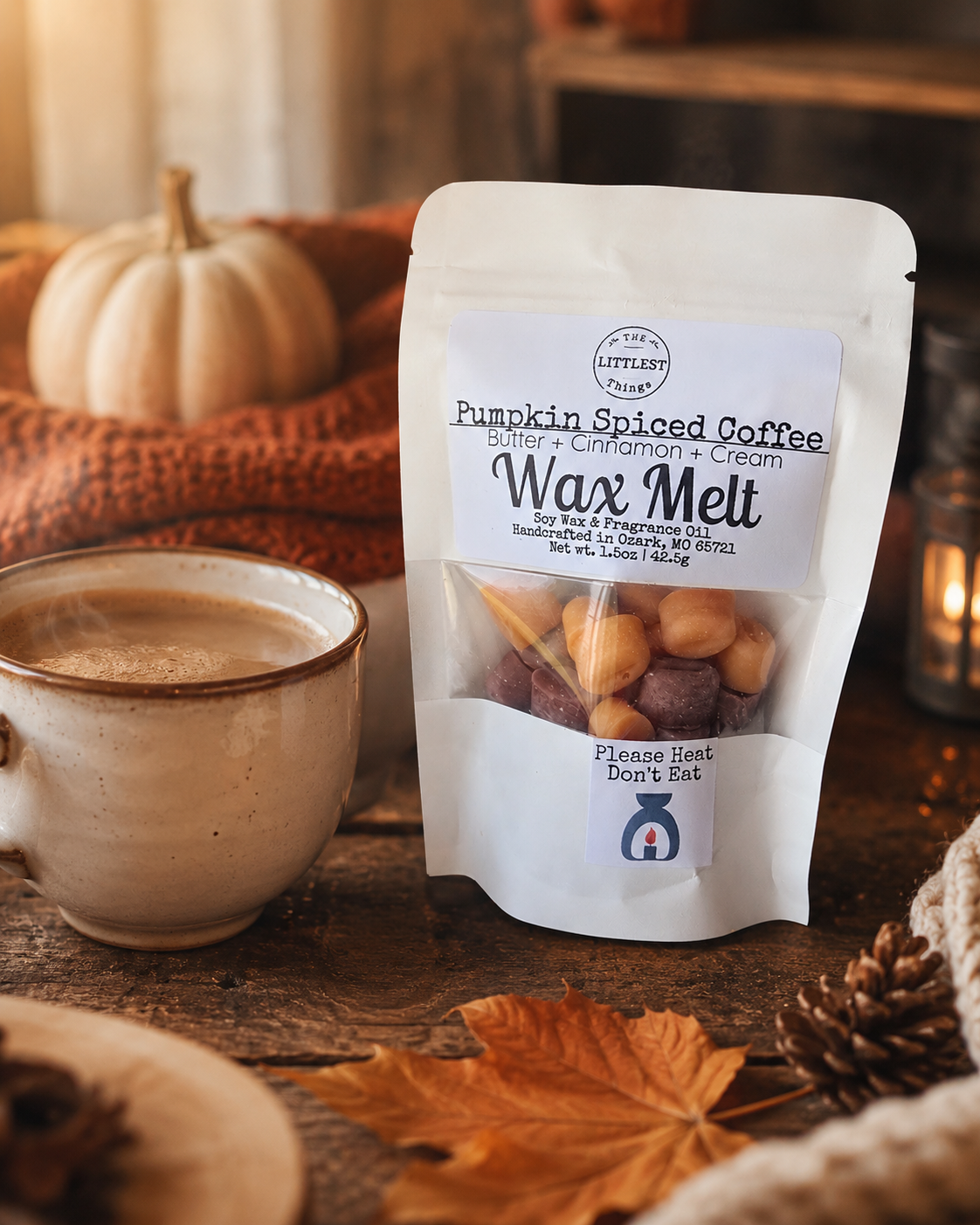 A stand-up pouch of Little Leaf Wax Melt coffee wax melts labeled 'Pumpkin Spiced Coffee' sits on a rustic wooden table beside a ceramic mug of coffee, with pumpkins, autumn leaves, and a candle in the background.