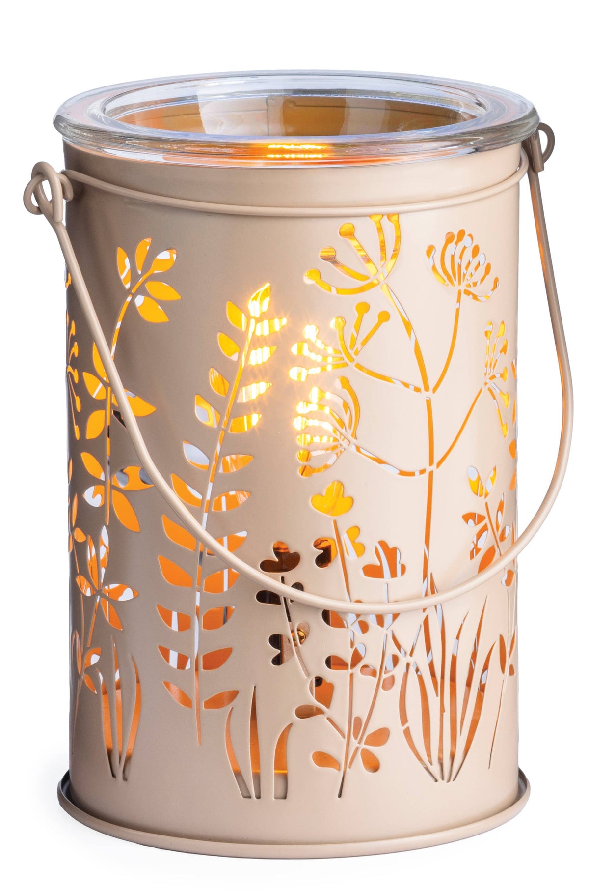 A cylindrical metal lantern with a warm beige finish, featuring a floral cutout pattern that reveals a glowing orange light inside. It has a clear glass top, a wire handle, and sits on a plain white background.