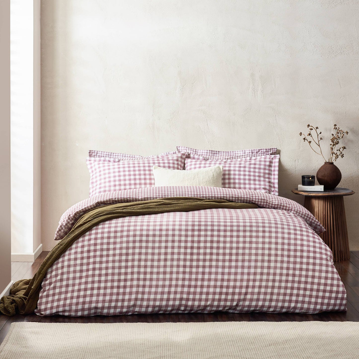 Bed with berry and white checkered bedding in a minimalistic room.