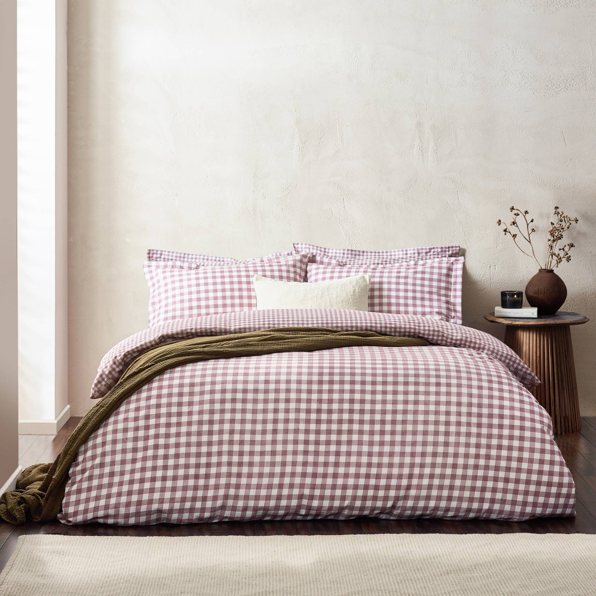 Bed with berry and white checkered bedding in a minimalistic room.