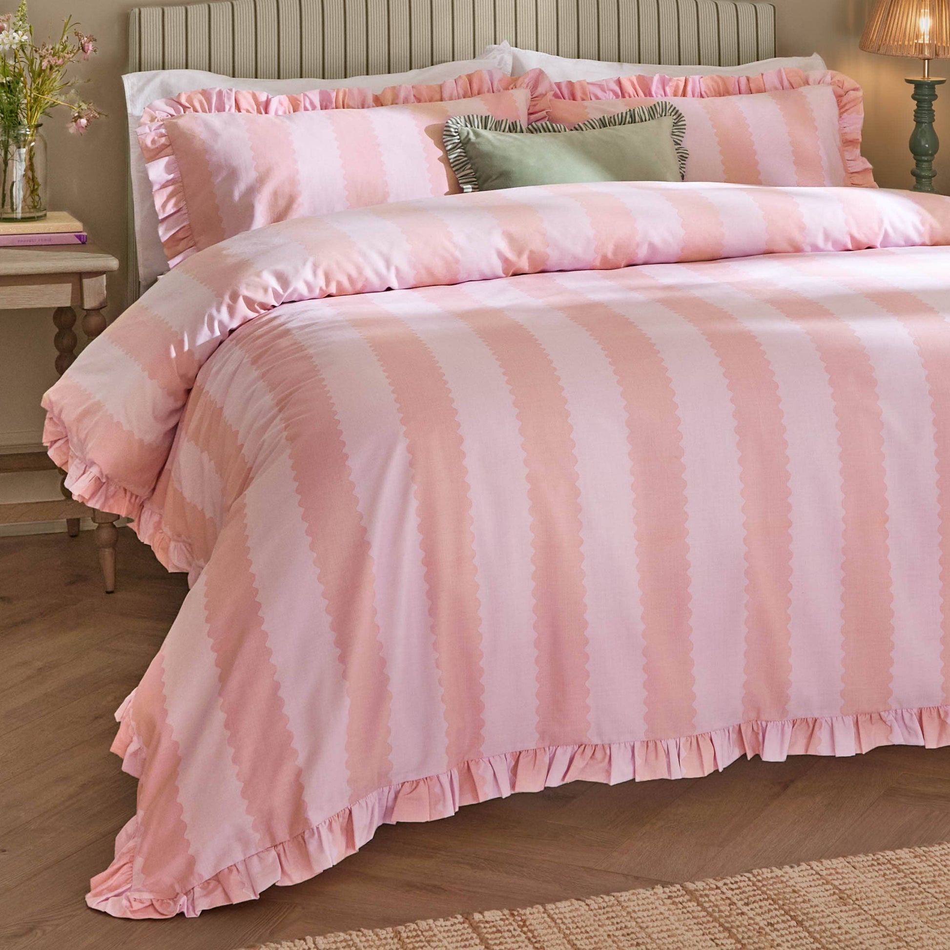 Pink striped bedding set on a bed in a bedroom setting.