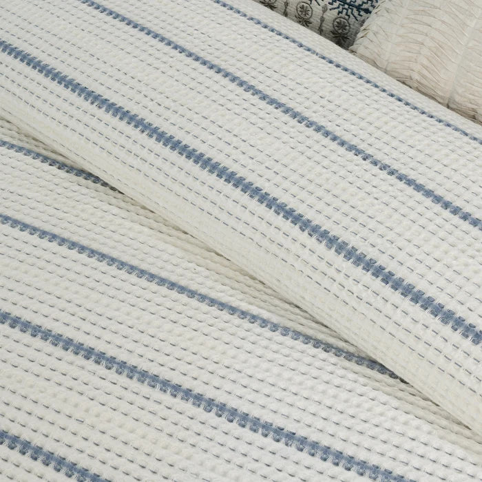 Close-up of Levtex Home Waffle Stripe Blue Comforter showing raised ivory waffle weave texture and woven blue horizontal stripes.
