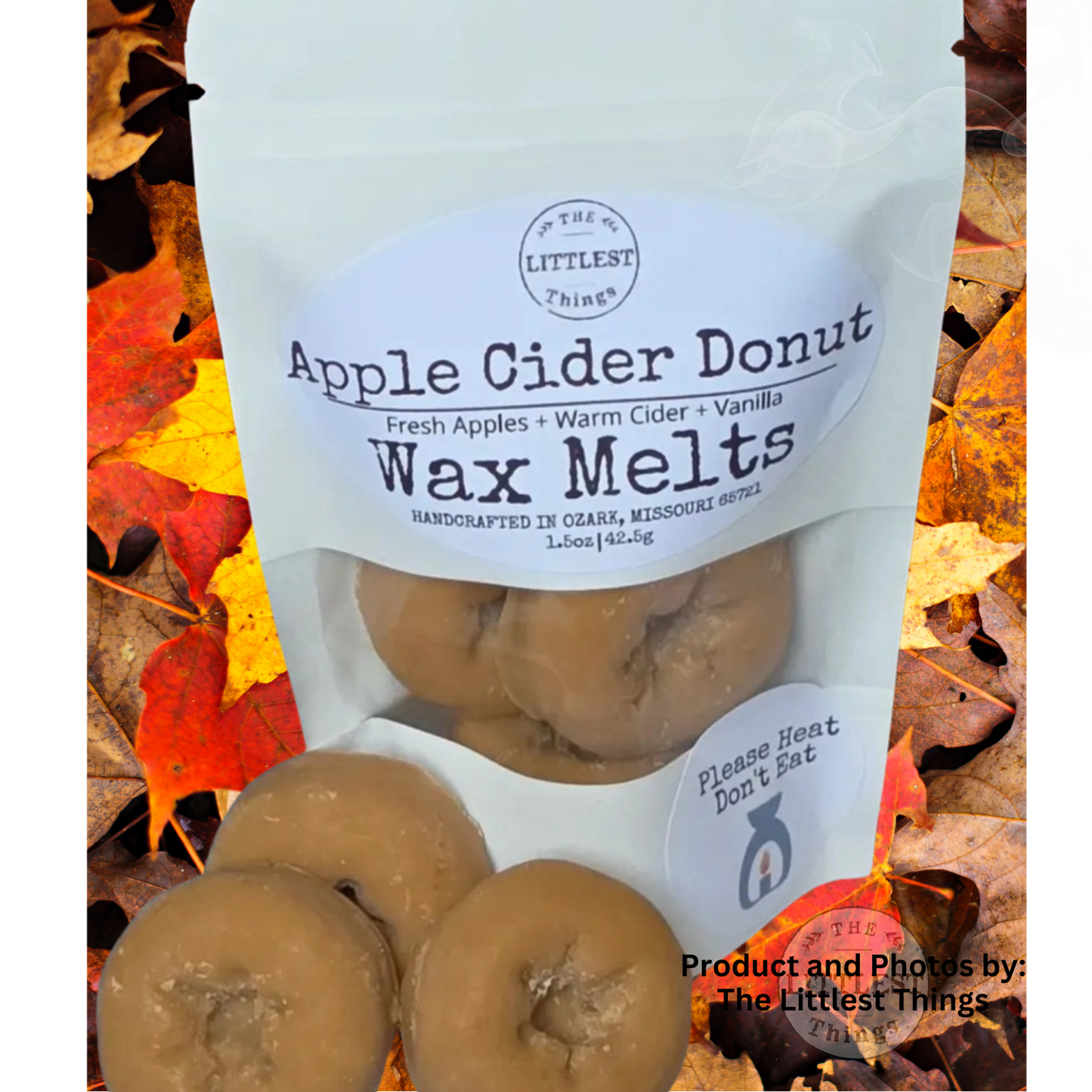 A stand-up pouch labeled 'Apple Cider Donut Wax Melts' by The Littlest Things, shown with several tan donut-shaped wax melts in front, set against a background of colorful autumn leaves.