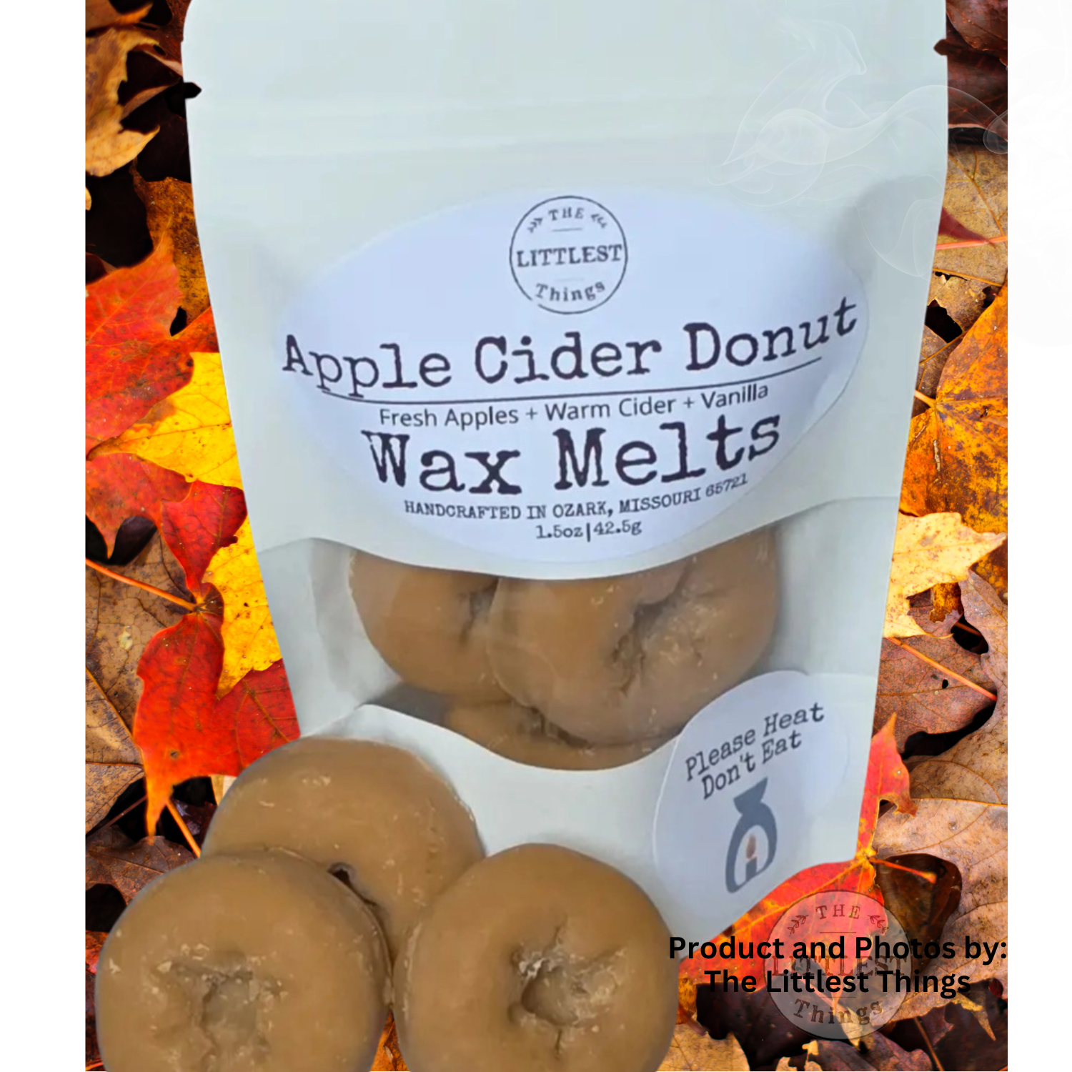 A stand-up pouch labeled 'Apple Cider Donut Wax Melts' by The Littlest Things, shown with several tan donut-shaped wax melts in front, set against a background of colorful autumn leaves.