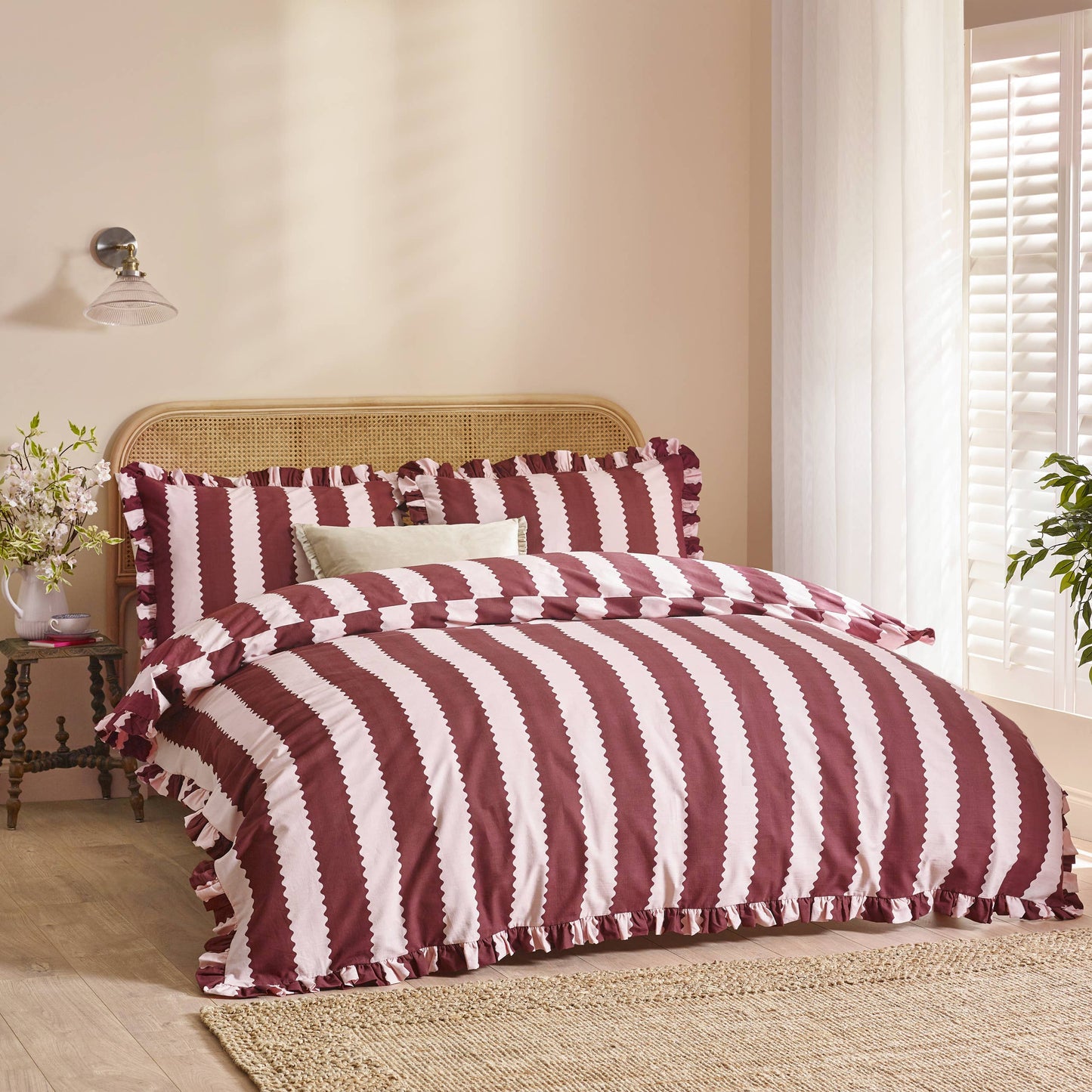 Bed with burgundy and blossom striped bedding in a bedroom setting.